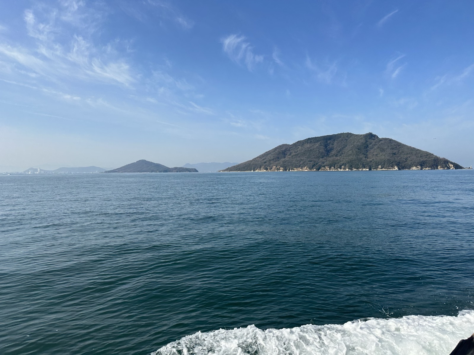 船の上から見た瀬戸内海。正面に緑の山を抱いた島が浮かんでいる